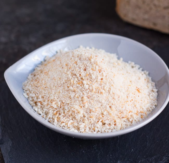 A small gray bowl full of dry breadcrumbs made from a loaf of old dry bread.  