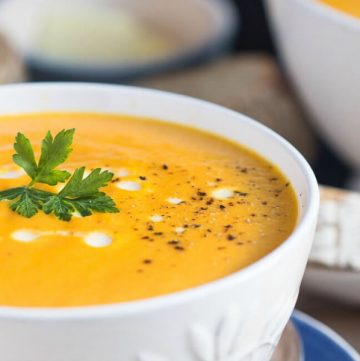 A white bowl full of creamy carrot soup.