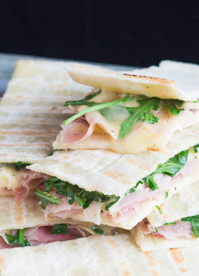 A close up shot of ham & brie flatbread sandwiches, clearly showing the flatbread filling. 