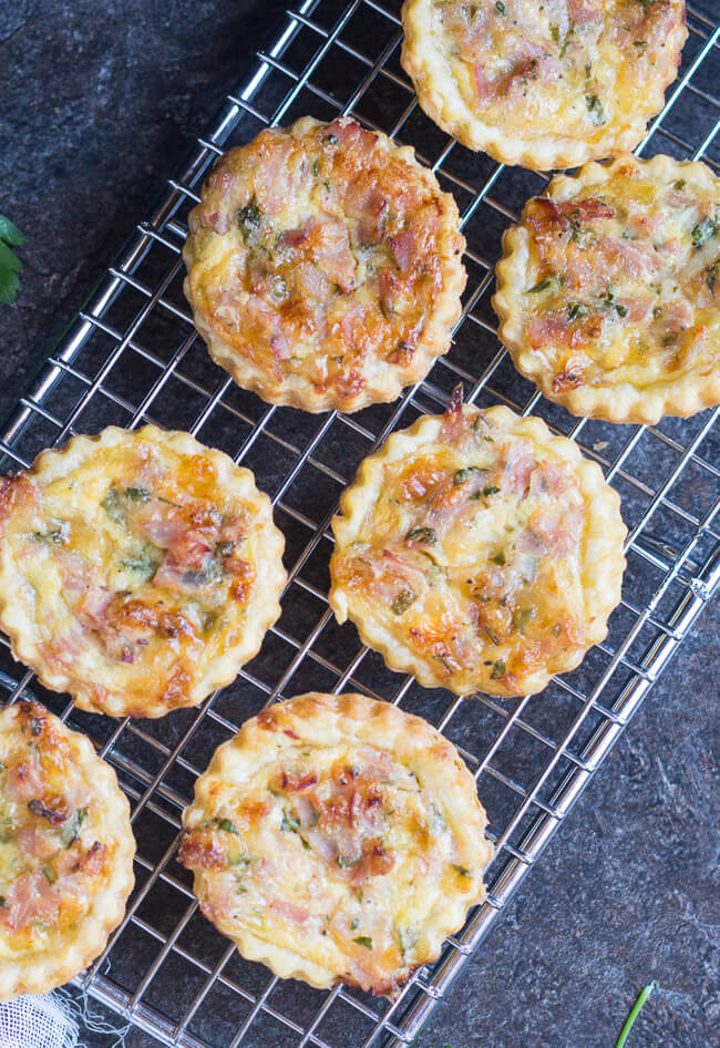 Overhead shot of seven mini quiches, made with this easy mini quiche recipe, on a cooling rack. 