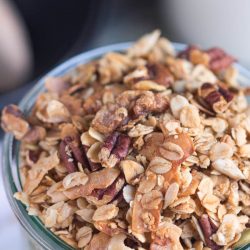 A close up shot of the homemade crunchy granola recipe, showing the cooked coconut flakes, crunchy nuts and rolled oats.