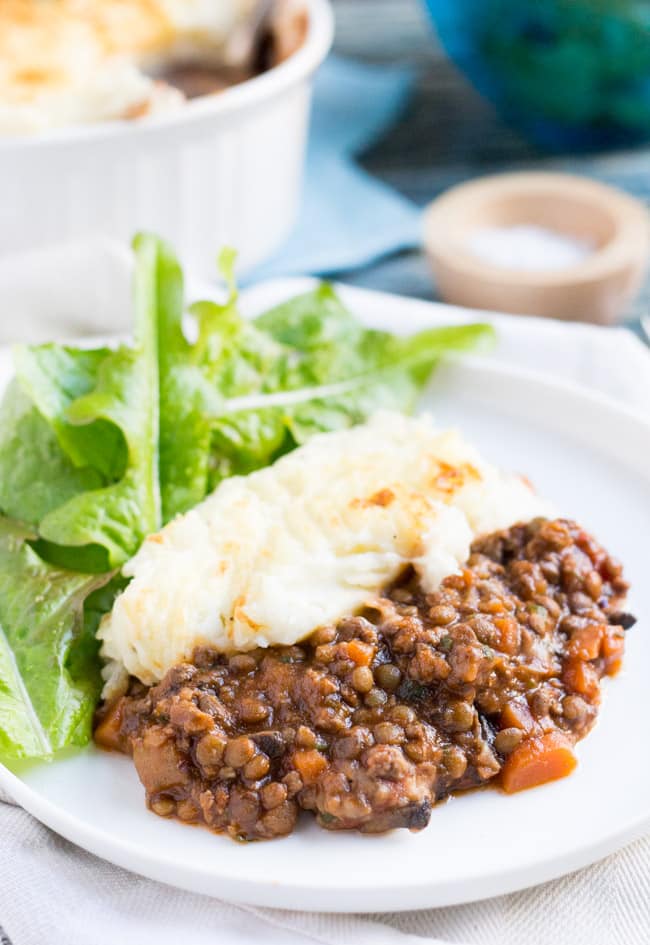 A single serve of healthy shepherd's pie with a green lettuce side salad on a white plate.  