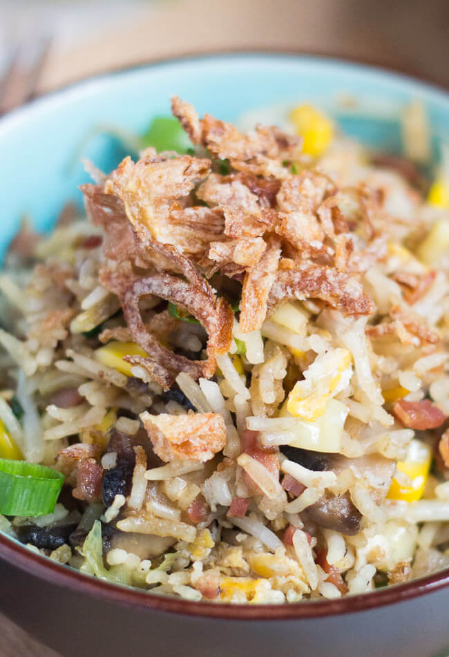 Close up of a fried rice recipe with leftover rice, with indiviual ingredients showing in the rice. A pile of crispy onions sit on top of the fred rice.