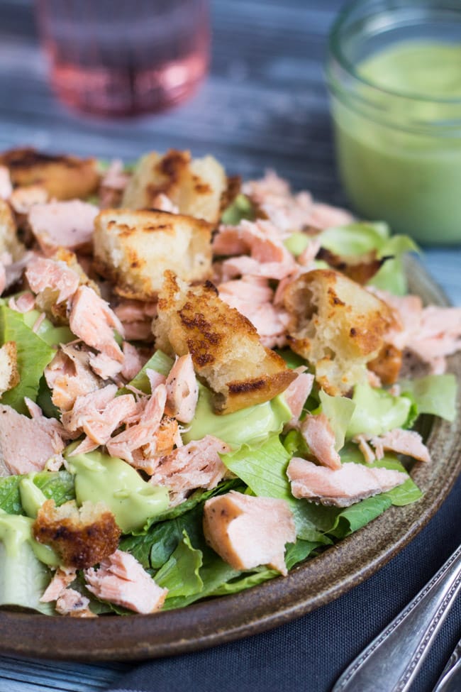 Flaked salmon and crispy homemade croutons on a bed of chopped Romaine lettuce, surrounded by blobs of creamy avocado dressing.  