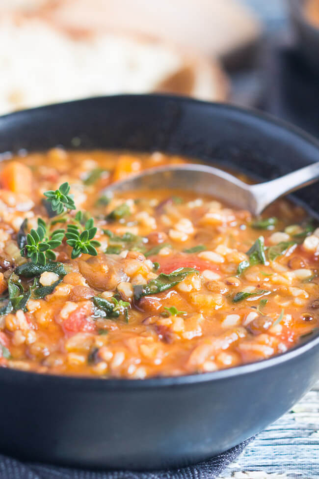 A black bowl, filled with a hearty lentil and brown rice soup recipe.