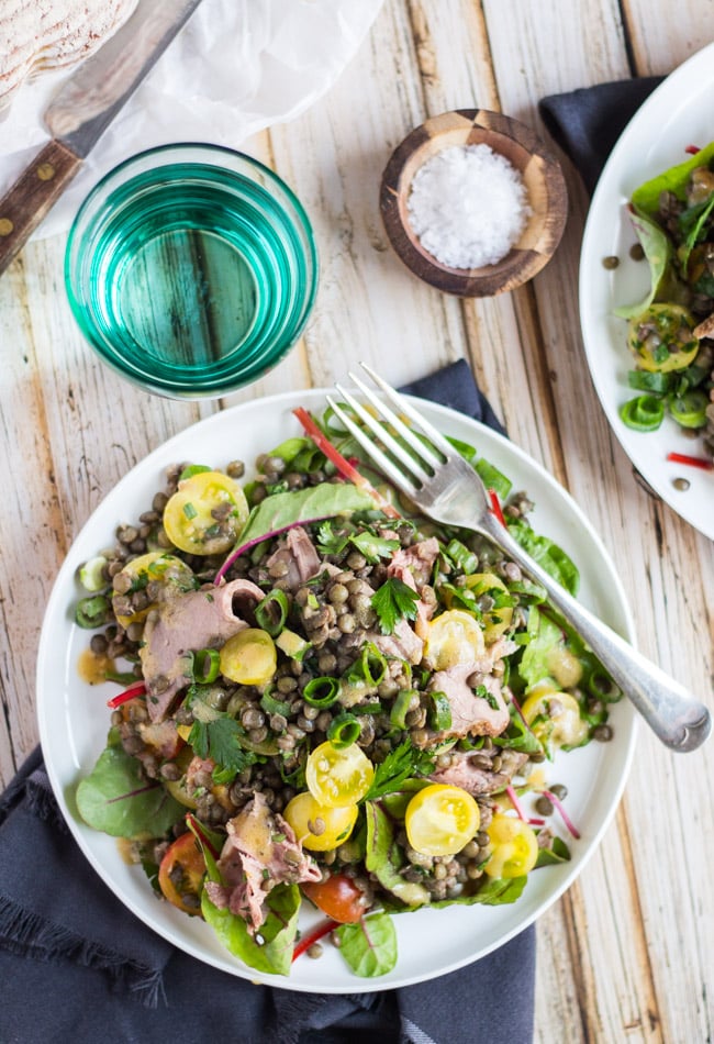 Overhead shot of an easy roast beef salad recipe, scattered with sliced spring onions, on a white plate. 