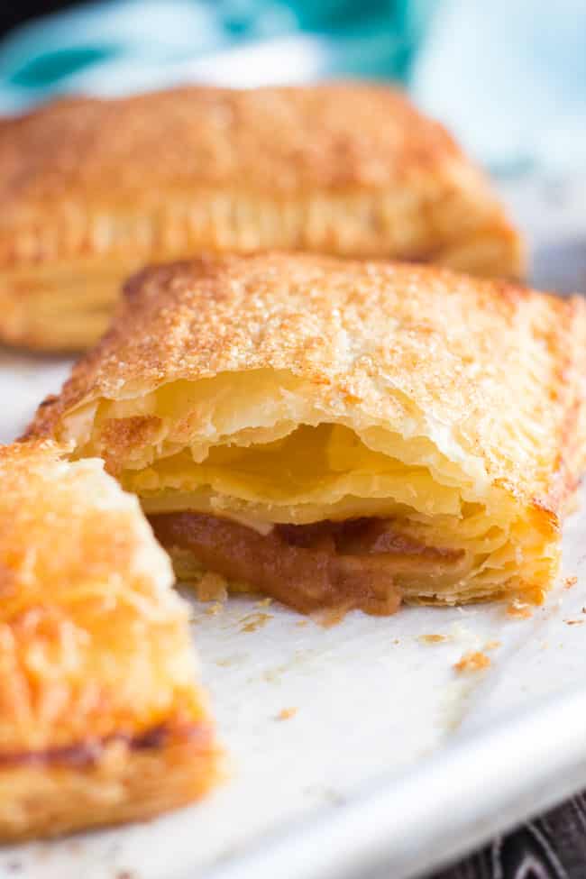 A close up shot of a cut apple turnover, made from an easy apple turnovers recipe, showing the applesauce filling and the flaky layers of the cooked filling. 