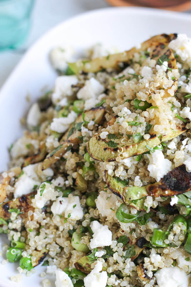 A close up view of the assembled quinoa, feta & grilled zucchini salad recipe.  Slices of grilled zucchini and crumbles of feta can be clearly seen.  