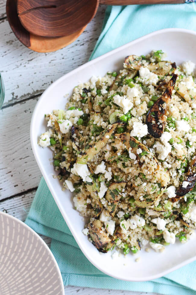 An overhead shot of a square white plate on a blue tea towel, piled high with the assembled quinoa, feta & grilled zucchini salad recipe.  