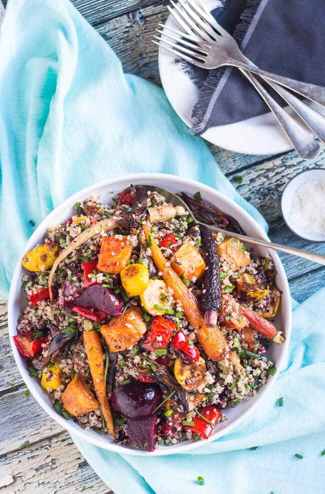An overhead shot of this easy Mediterranean quinoa salad recipe packed with roasted vegetables in a white bowl, sitting on a blue tea towel.