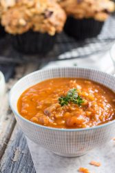 A small bowl of red lentil & smoky bacon soup, with feta muffins in the background.