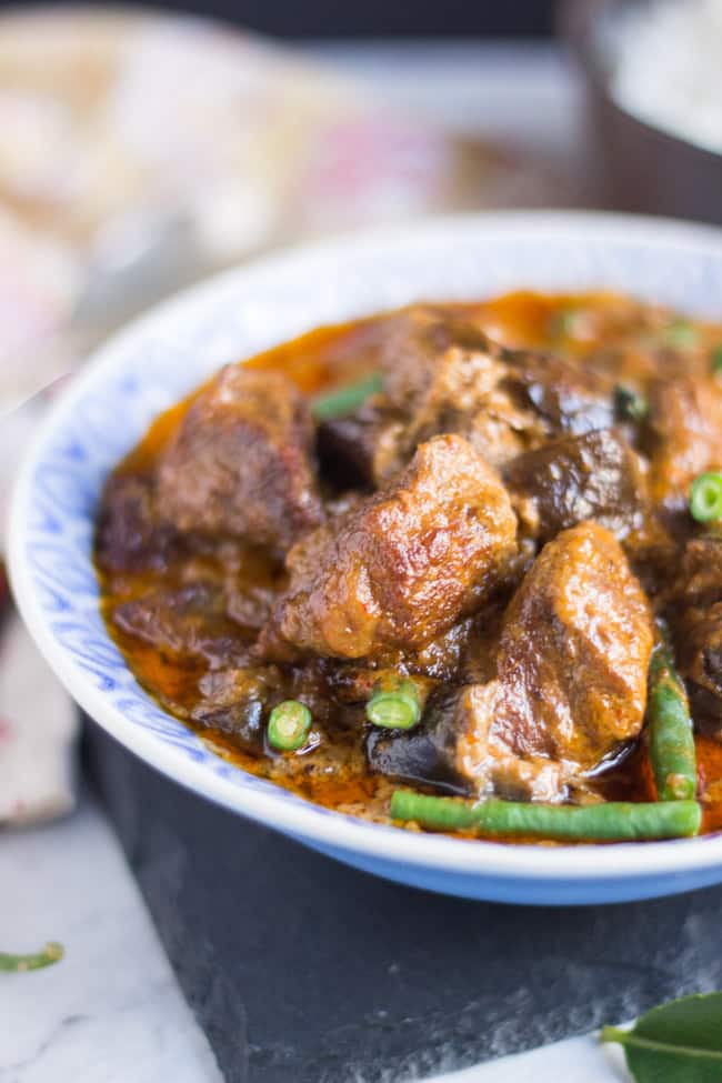 A blue & white patterned bowl, filled with slow cooker Thai red beef curry, showing chunks of beef, eggplant & green beans in a thick red gravy. 
