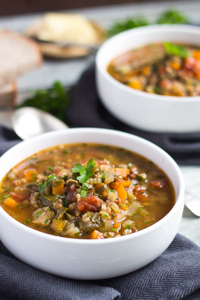 Two white bowls brimming with a slow cooker vegetable soup made with soup mix. 