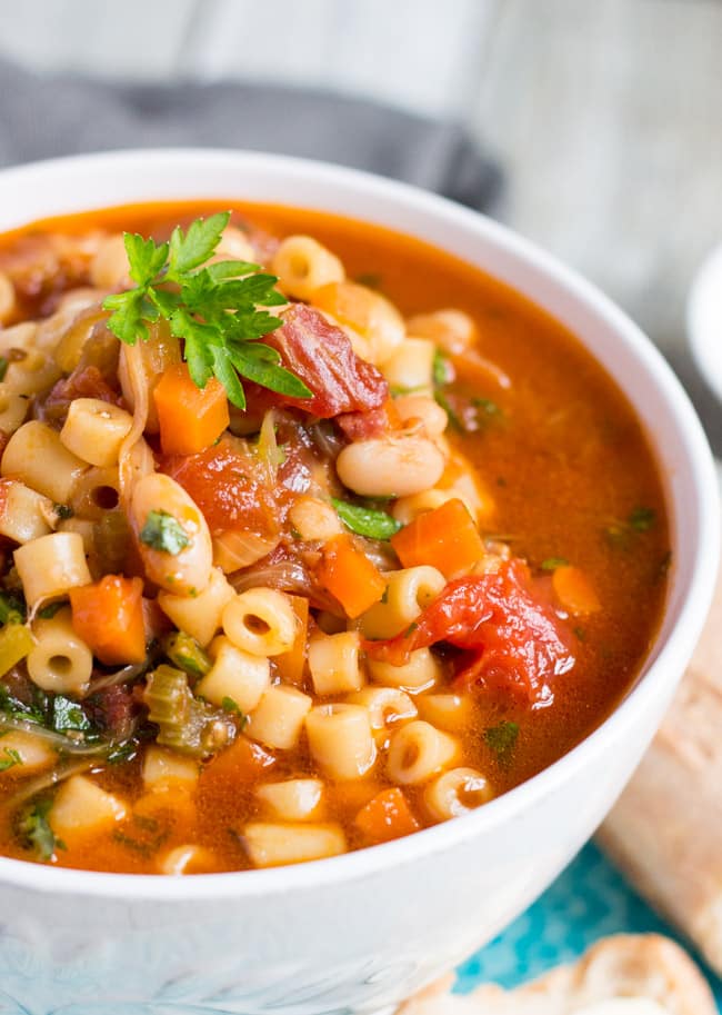 Close up shot of easy Minestrone Soup in a white bowl, showing pasta, beans and vegetables