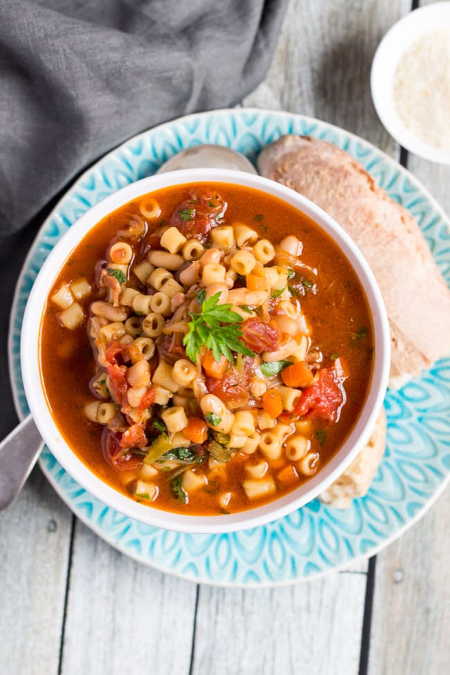 Overhead shot of a white bowl full of easy minestrone soup sitting on a blue and white plate. 