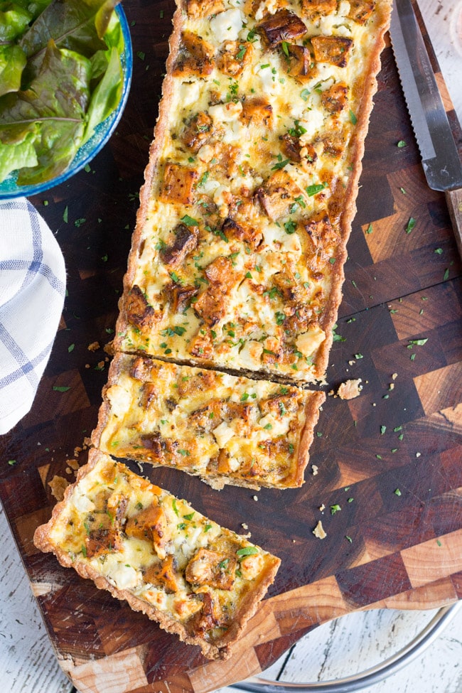 Overhead shot of a baked Sweet Potato, Feta & Caramelised Onion Tart on a wooden board. 