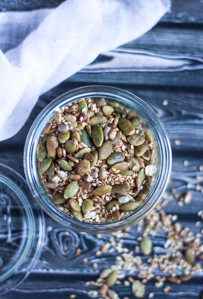 Overhead view of a glass jar full of a tamari seed mix containing pumpkin, sunflower and sesame seeds.  