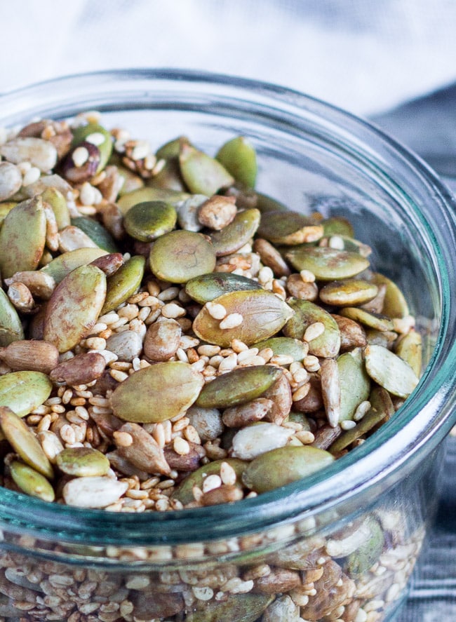 Close up of toasted pumpkin, sunflower and sesame tamari seeds in a glass jar.  