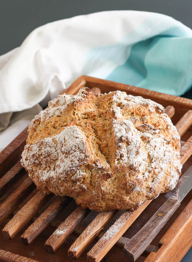 An uncut loaf of traditional Irish soda bread on a bread board.