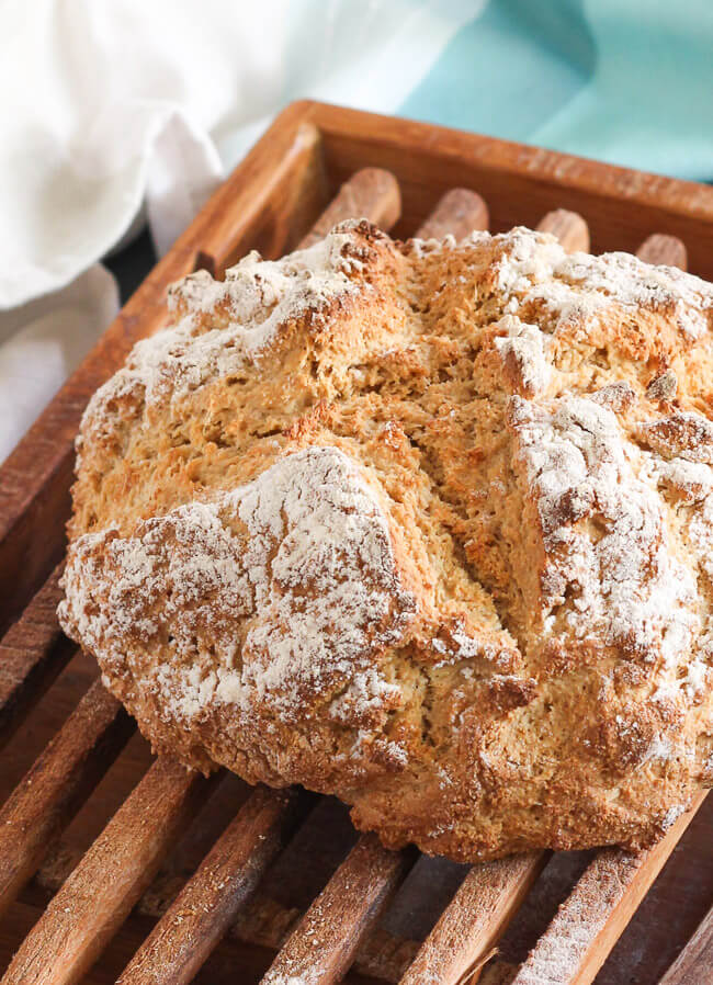 A close shot of a loaf of traditional Irish soda bread on a bread board. 